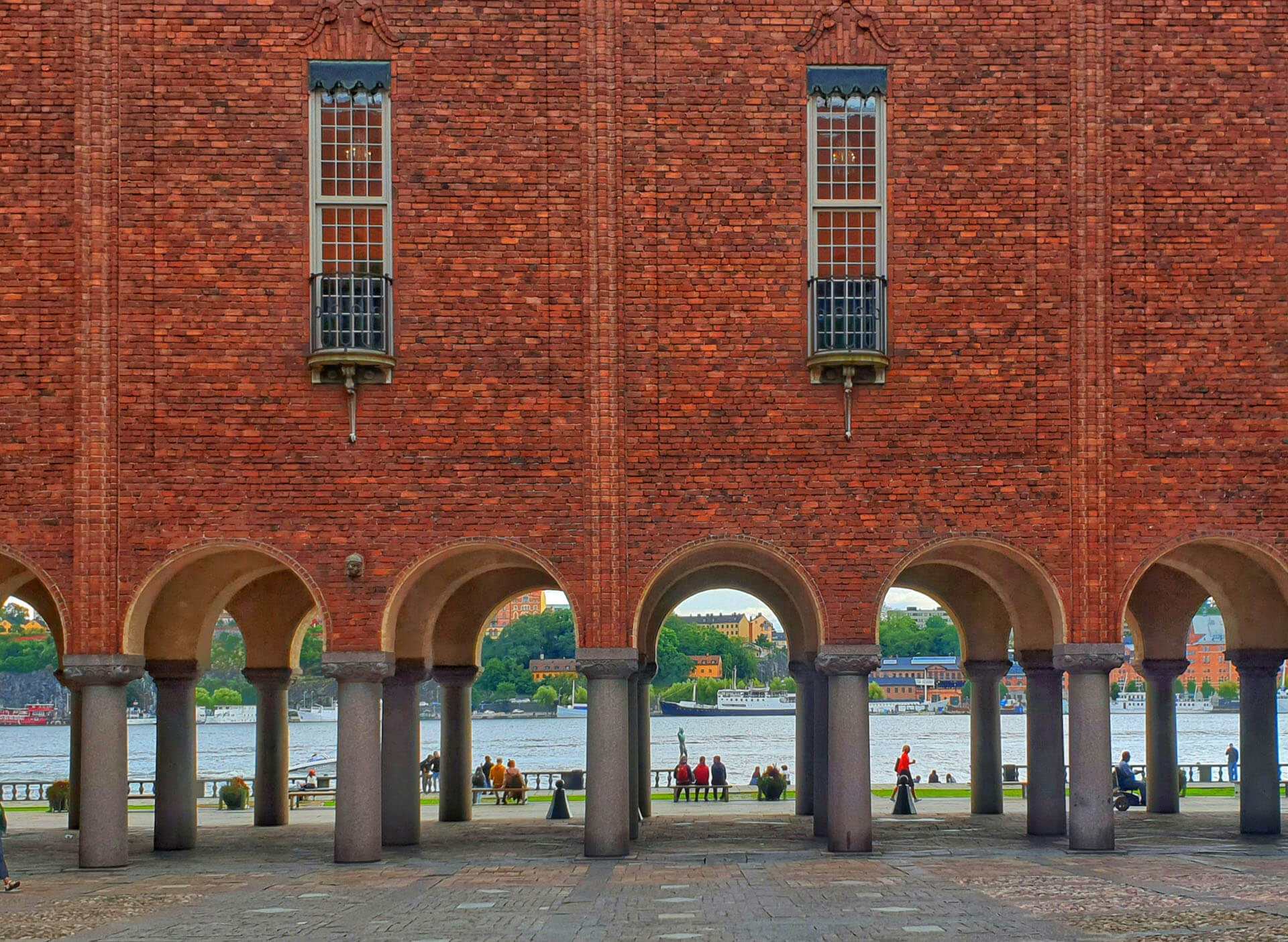Bild av Stockholms Stadshus med röda tegelväggar, valvbågar och utsikt över vattnet. Den ikoniska byggnaden är en populär plats för borgerlig vigsel i Stockholms Stadshus och bröllopsfotografering i Stockholm.