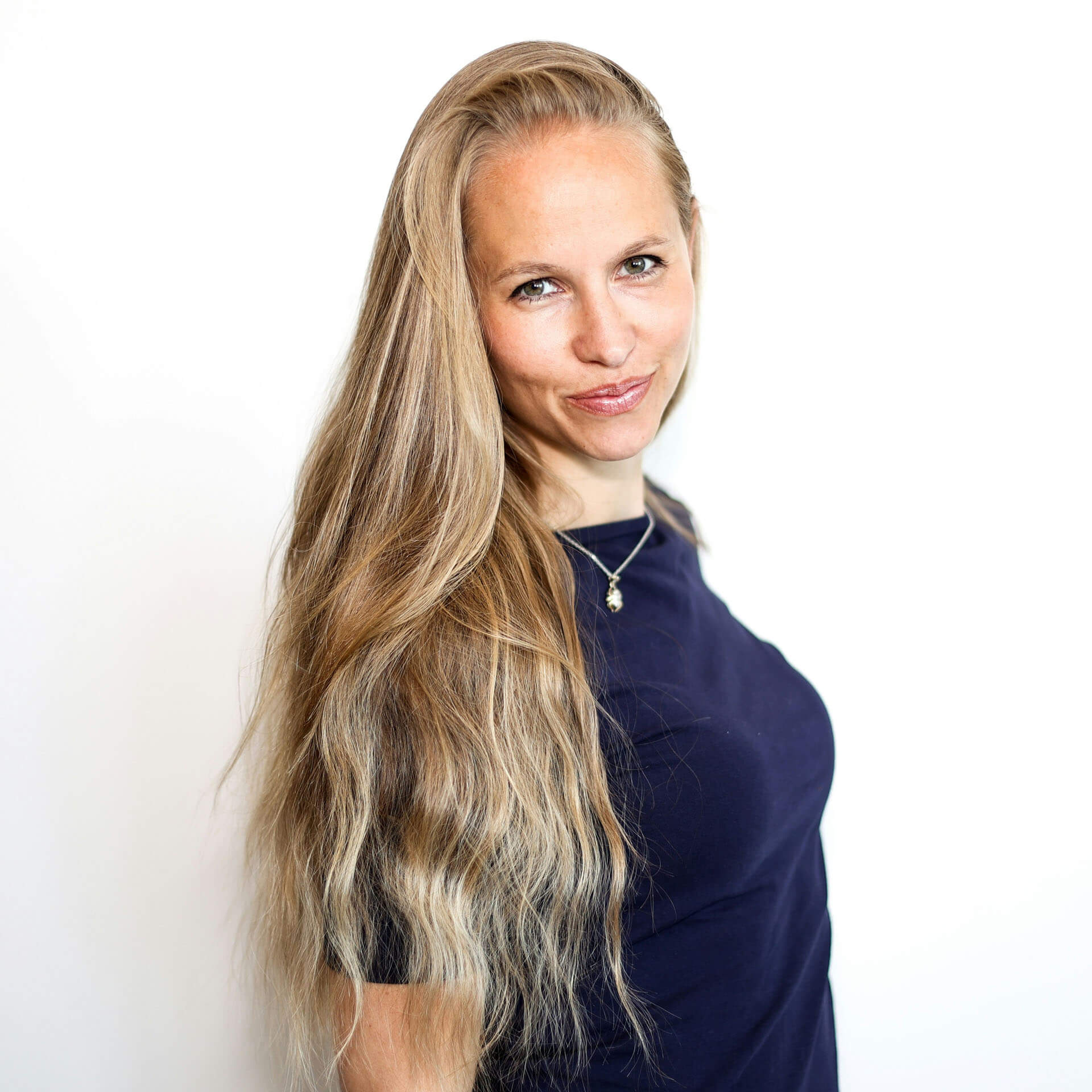 Företagsporträtt i studio i Stockholm där person med långt hår uppsatt i ett diadem fotograferas mot en ljus bakgrund. Studioljuset framhäver ansiktsdrag och skapar ett ledigt men professionellt personalfoto.