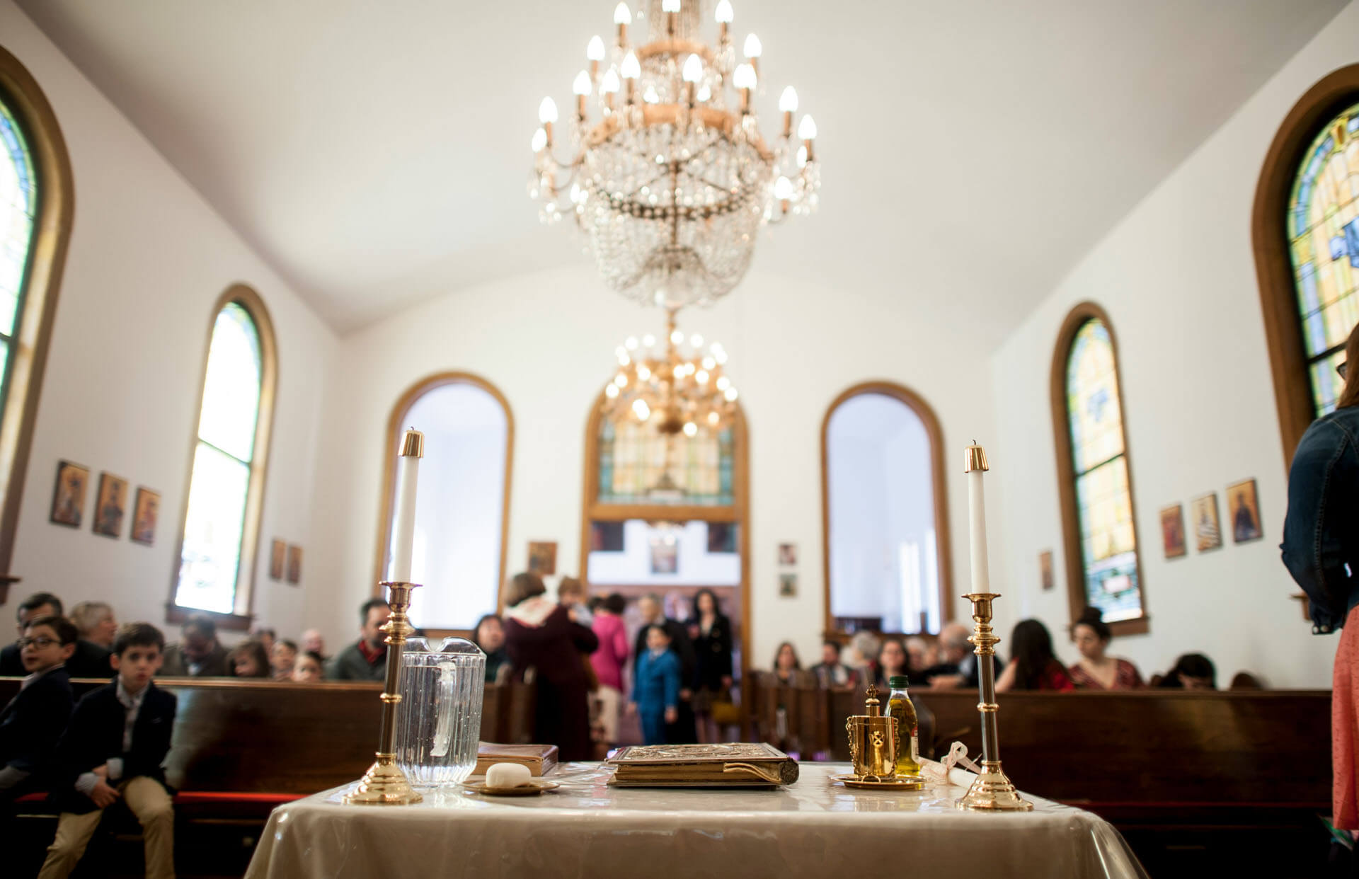 Kyrkointeriör med dopbord, ljus och gäster inför dopceremoni.