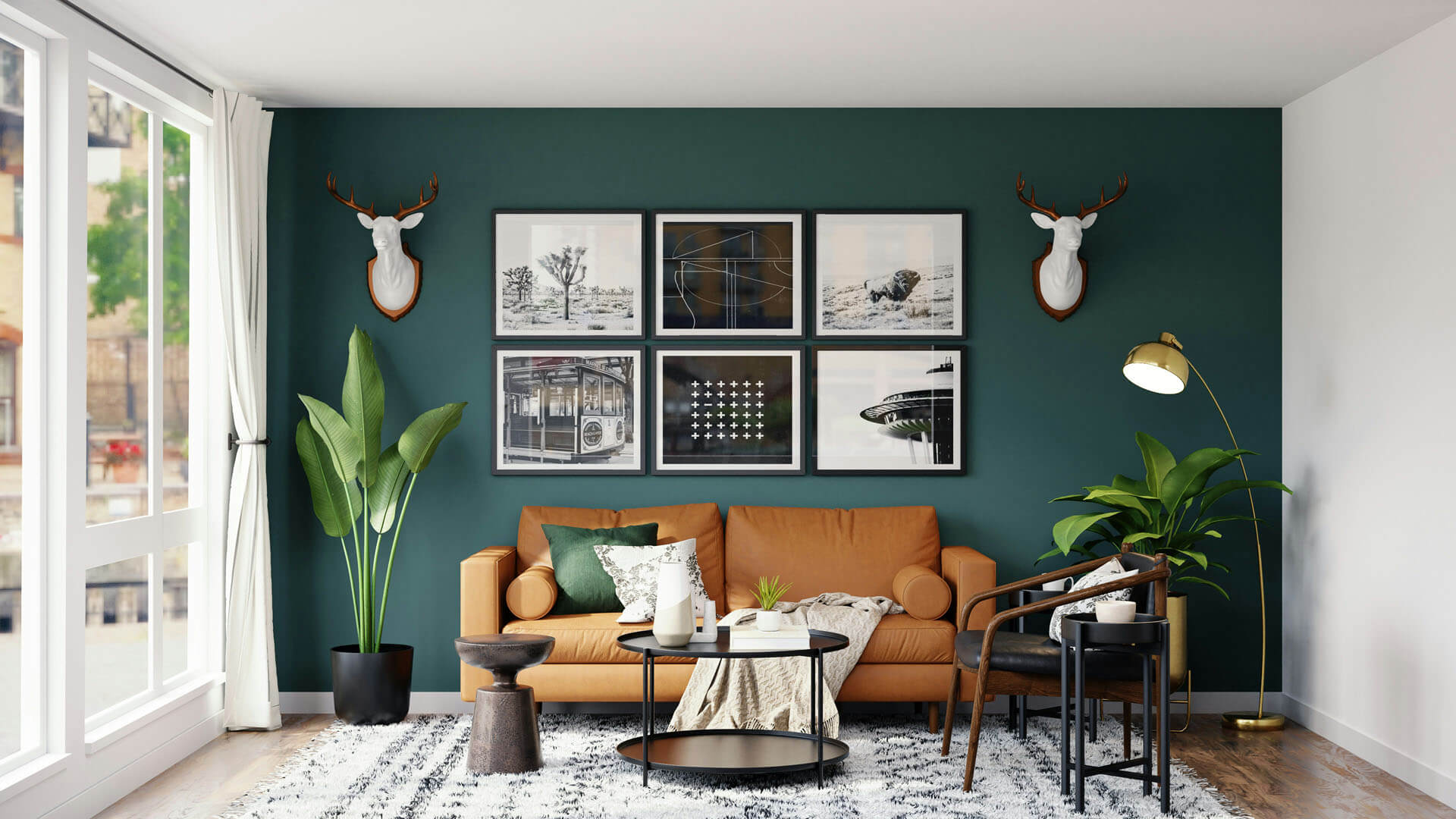 Vardagsrum med grön fondvägg, brun soffa, inramade bilder och stora växter, fotograferat i naturligt ljus från ett fönster till vänster.