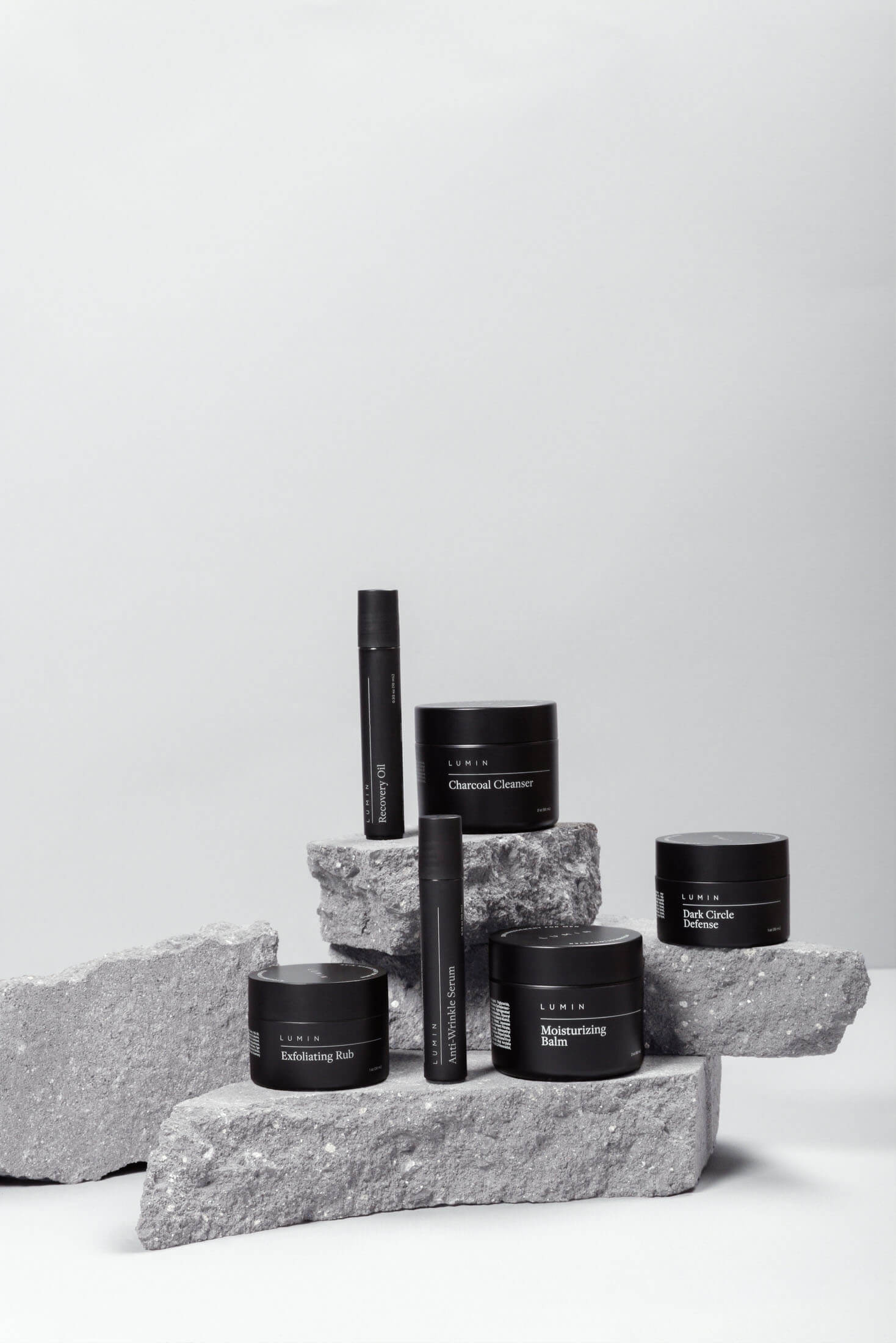 Produktfotografering i Stockholm där svarta hudvårdsprodukter är placerade på oslipade stenblock. De ljusa stenarnas naturliga struktur skapar kontrast mot de mörka runda förpackningarna och framhäver produktdesign, detaljer och varumärkets exklusiva känsla i professionella produktbilder för e-handel och marknadsföring.