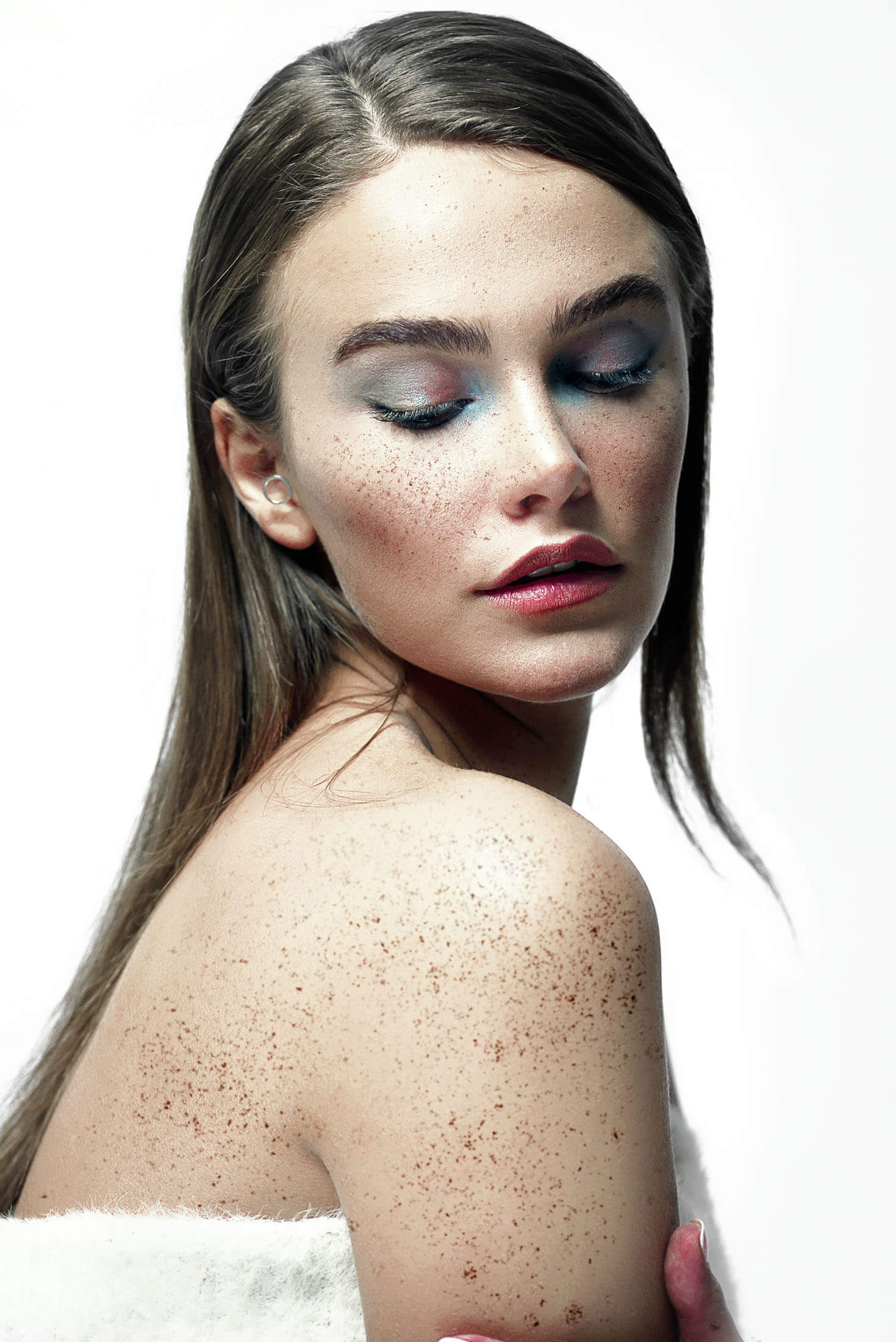 Porträtt i studio på en kvinna med fräknar och färgstark ögonmakeup fotograferat av fotograf i Stockholm. Bilden visar professionell retuschering av bilder där hudstruktur, färger och detaljer bevaras naturligt.