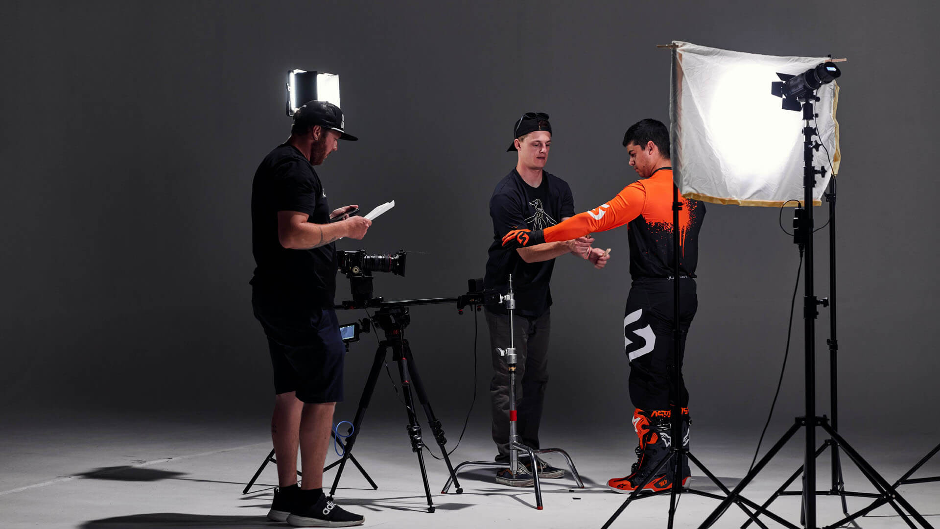 Reklamfotografering i studio där ett fototeam arbetar med kamerarigg, och ljusutrustning medan en modell förbereds inför fotografering. Bilden visar arbetet bakom professionell reklamfotografering i Stockholm.