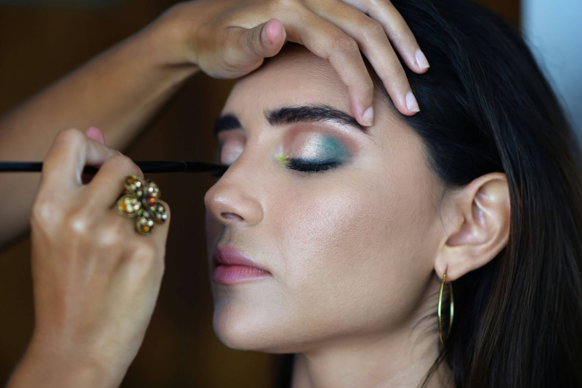 Närbild från studiofotografering i Stockholm där en makeupartist applicerar ögonskugga på en modell inför fotografering. Bilden visar professionell bildretuschering, och färgkorrigering med fokus på makeup.