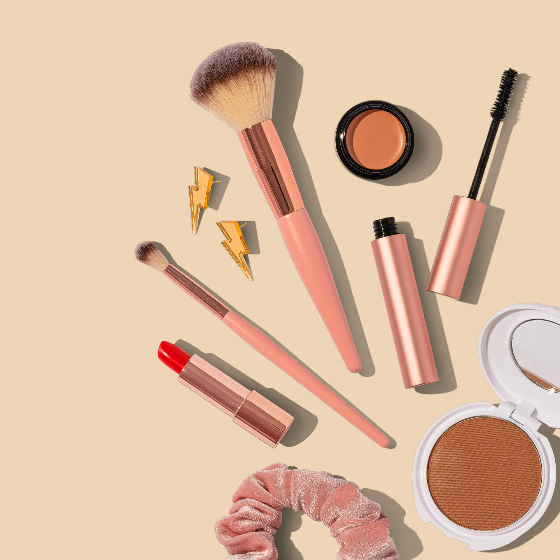 Produktfoto taget av produktfotograf i Stockholm där sminkborstar, mascara, läppstift och puder presenteras i en harmonisk studiokomposition. De varma tonerna och den mjuka belysningen framhäver produkternas kvalitet och skapar professionella produktbilder för webbshop, reklam och marknadsföring.